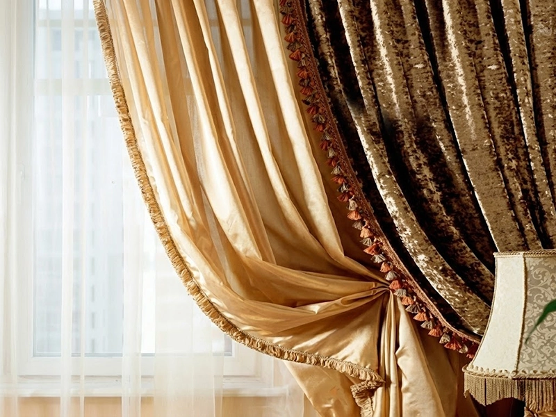 Окно, оформленное красными и бежевыми портьерами с легким белым тюлем