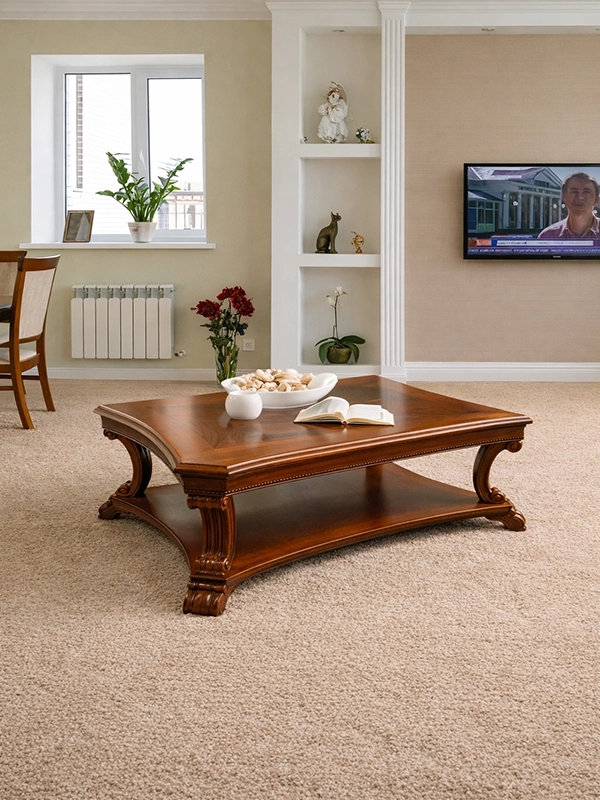 Круглый журнальный столик со стеклянной поверхностью на изогнутых металлических ножках в комнате