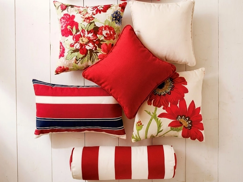 Композиция из красных и бежевых декоративных подушек на светлом диване