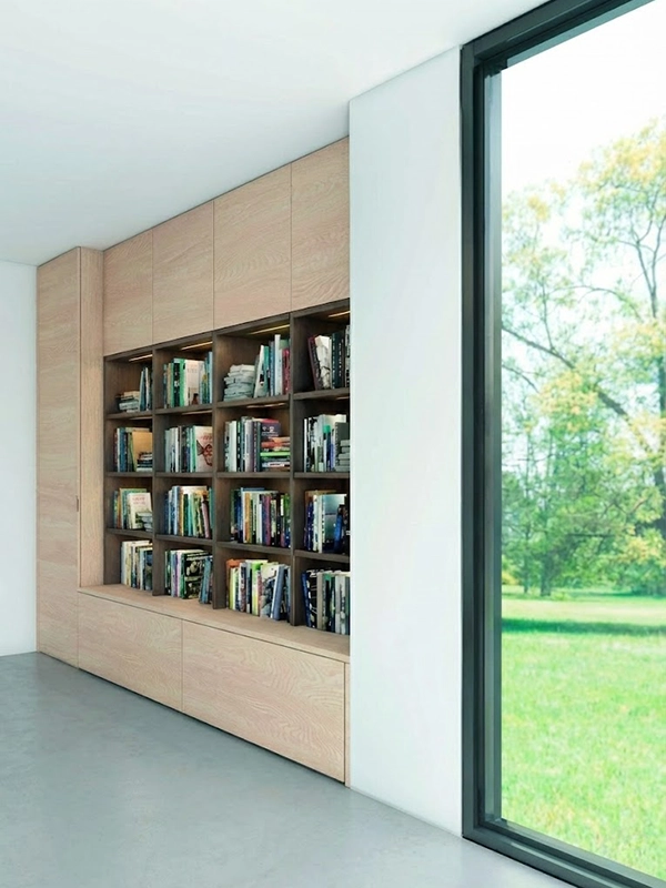 Уютный уголок в спальне с высокими книжными стеллажами, мягким креслом и напольным торшером у окна