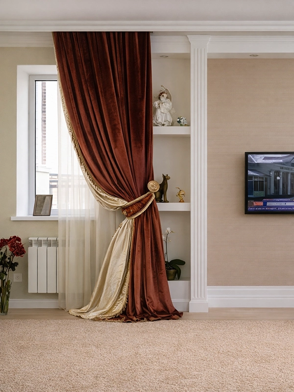 Комплект декоративных подушек бордового и бежевого цветов, разложенных на светлой мягкой мебели