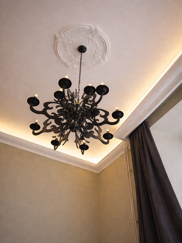 Черная дизайнерская люстра в центре белого потолка