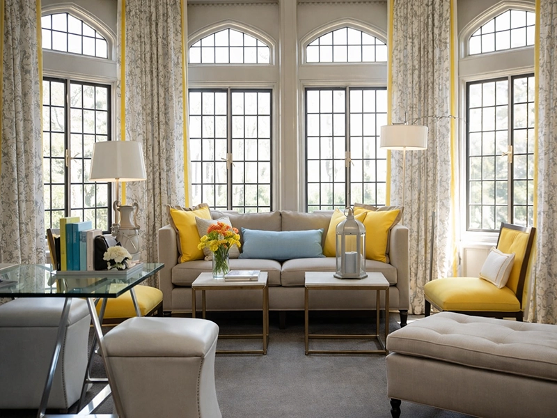 Просторная светлая гостиная с серым мягким диваном, оранжевым декором и панорамным окном в современном стиле.