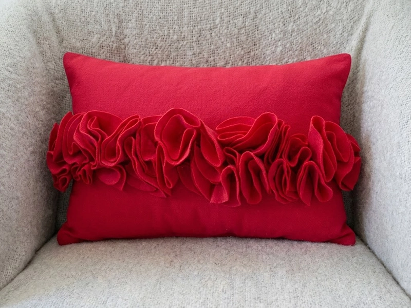 Красная бархатная декоративная подушка на светлом диване крупным планом