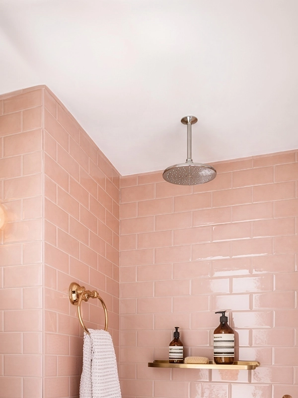 Душевая зона в ванной с розовой глянцевой плиткой на стенах и смесителем